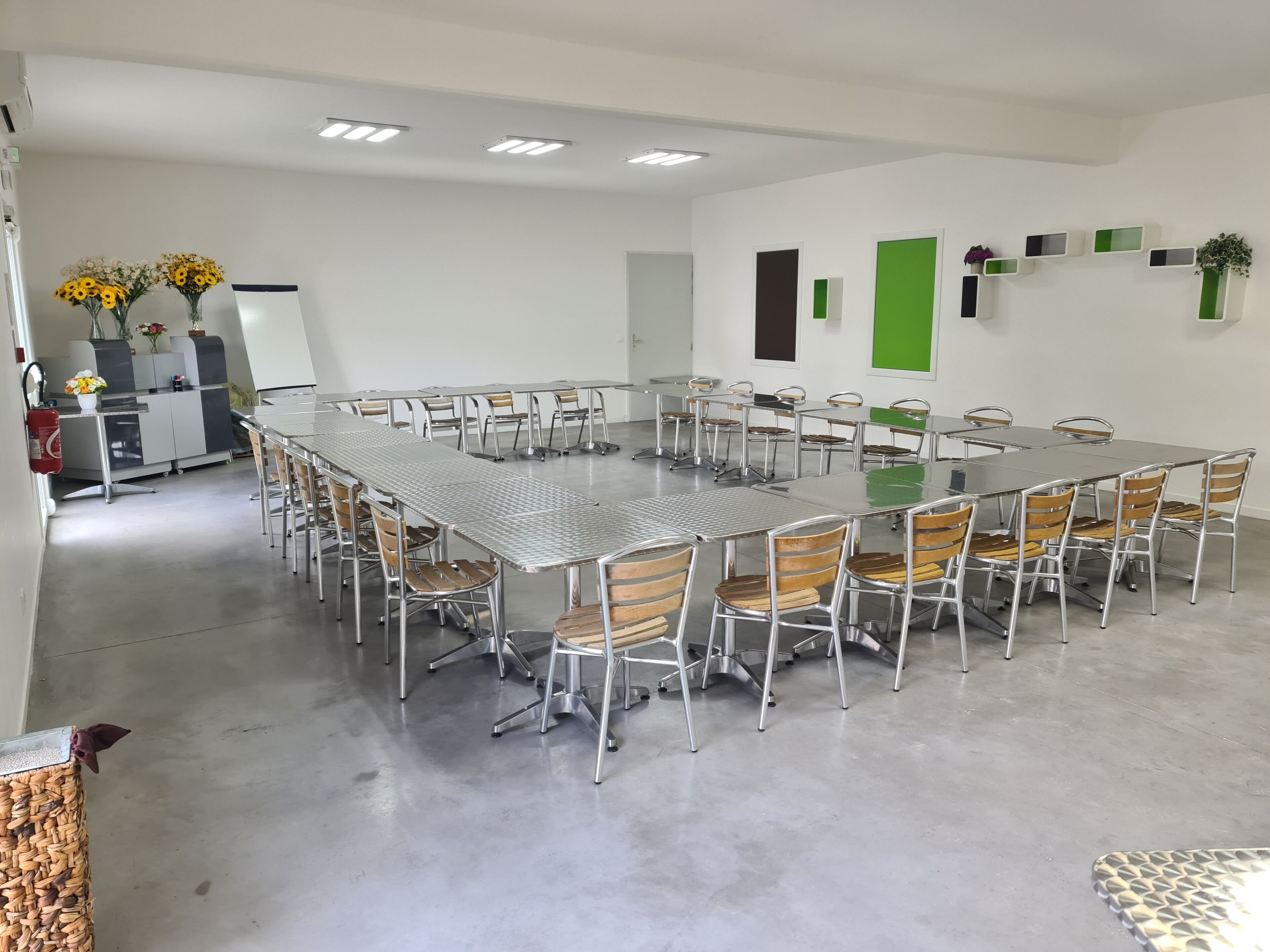 A conference room with a long table and chairs, white walls, and ceiling lights.