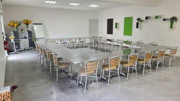 A conference room with a long table and chairs, white walls, and ceiling lights.