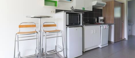 A modern kitchen with two bar stools, a microwave, a coffee maker, and cabinets.