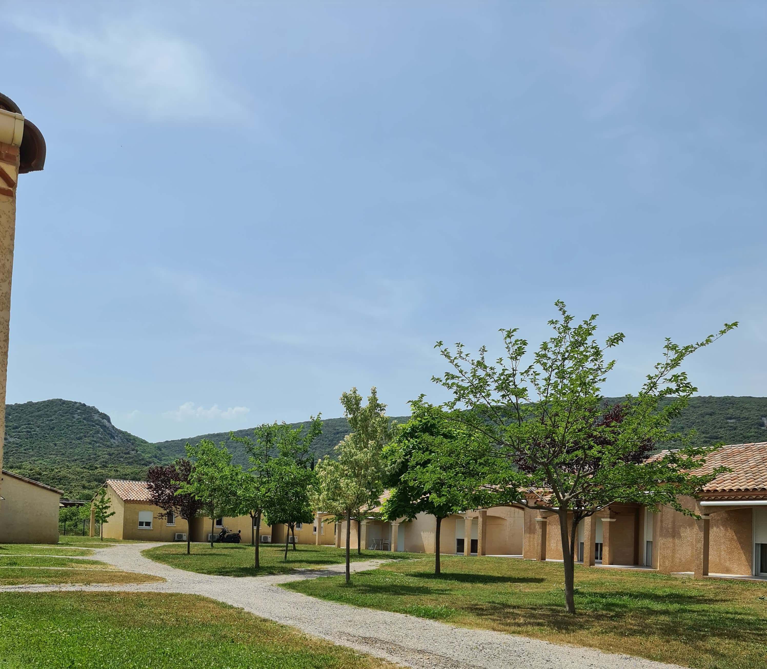 A courtyard with buildings, a gravel path, and trees.