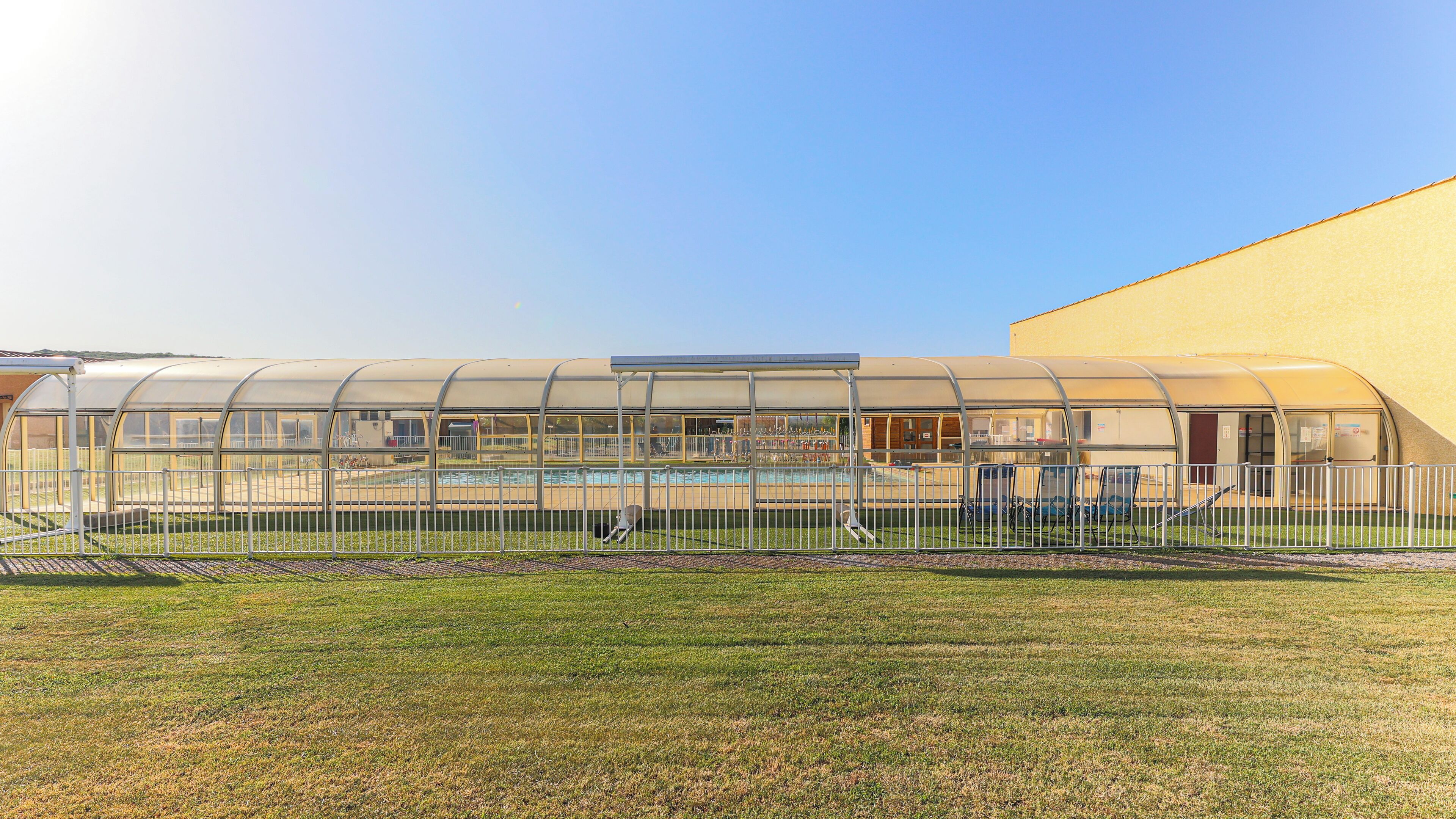A greenhouse structure with a pool and a fenced area.