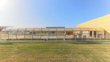 A greenhouse structure with a pool and a fenced area.