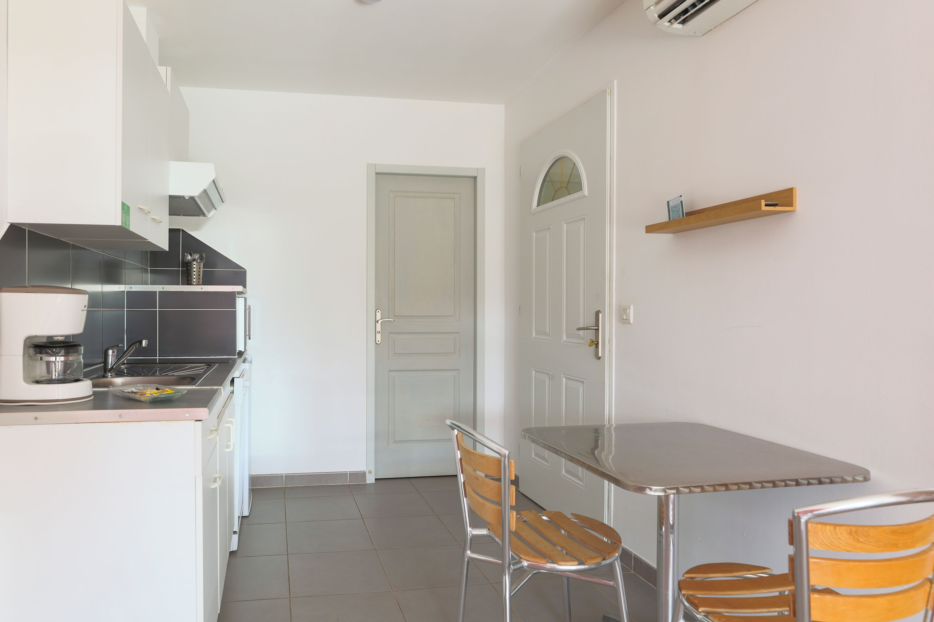 A compact kitchen with a dining area, including a table and two chairs.