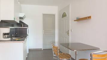 A compact kitchen with a dining area, including a table and two chairs.