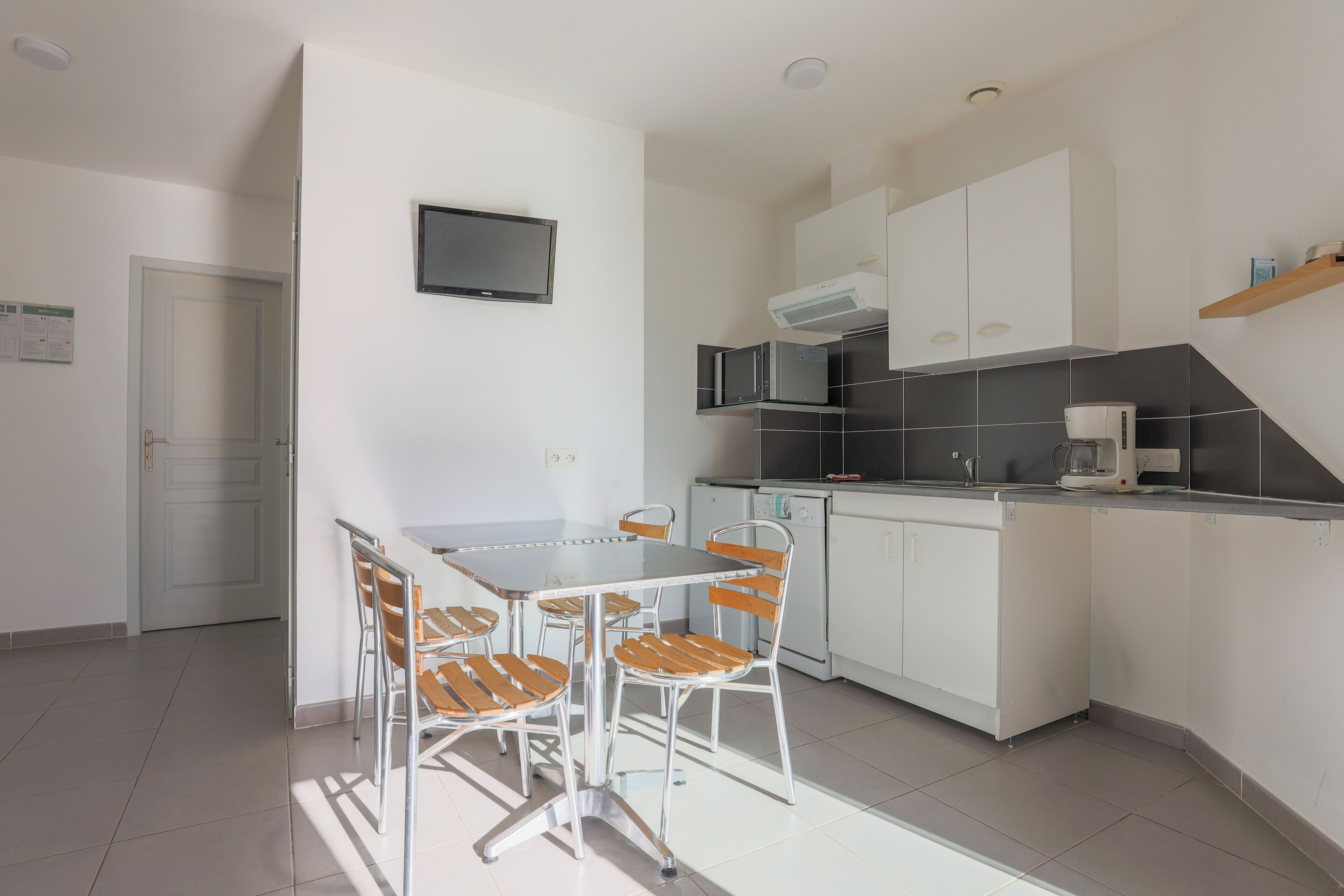 A modern kitchen with white cabinets, a built-in microwave, and a coffee maker.