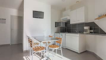 A modern kitchen with white cabinets, a built-in microwave, and a coffee maker.