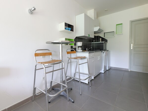 A modern kitchen with two bar stools, a coffee machine, and a microwave.