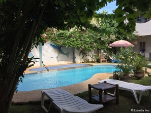 A swimming pool with lounge chairs and a mural on the wall.