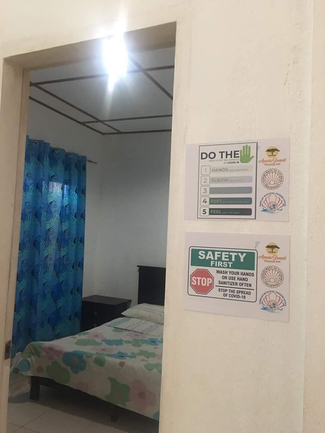 A bedroom with a bed, a blue curtain, and two safety posters on the wall.