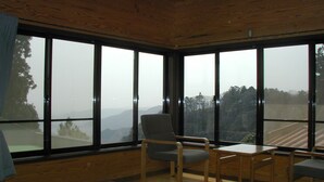 Una habitación con ventanas amplias, techo de madera y una mesa con sillas.