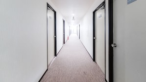 A long, narrow hotel corridor with doors on both sides, carpeted floor, and a sign indicating room number 706.
