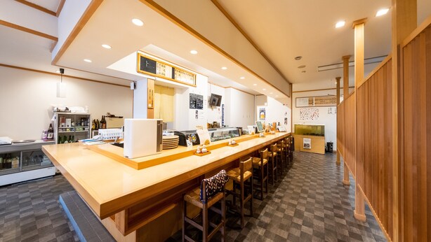 A modern bar area with a long counter, stools, and a checkered floor.