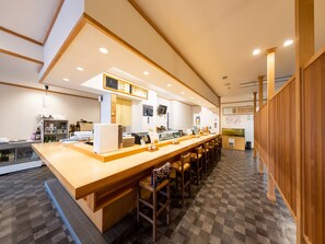 A modern bar area with a long counter, stools, and a checkered floor. - Tabist Hotel Tetora Hakodate Station (Hakodate)