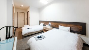 A hotel room with two beds, a desk, and a chair.