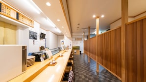 A restaurant interior with a long counter, wooden paneling on one side, and a tiled floor.