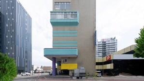 A modern building with a unique architectural design, featuring a mix of vertical and horizontal lines, a prominent entrance, and a parking garage.
