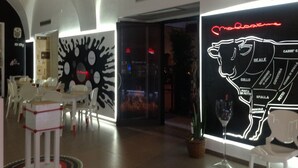 A modern interior with white furniture, a red lamp, and a neon sign of a cow.