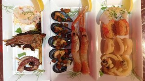 A seafood platter with various dishes including shrimp, mussels, and squid, garnished with lemon slices and herbs.