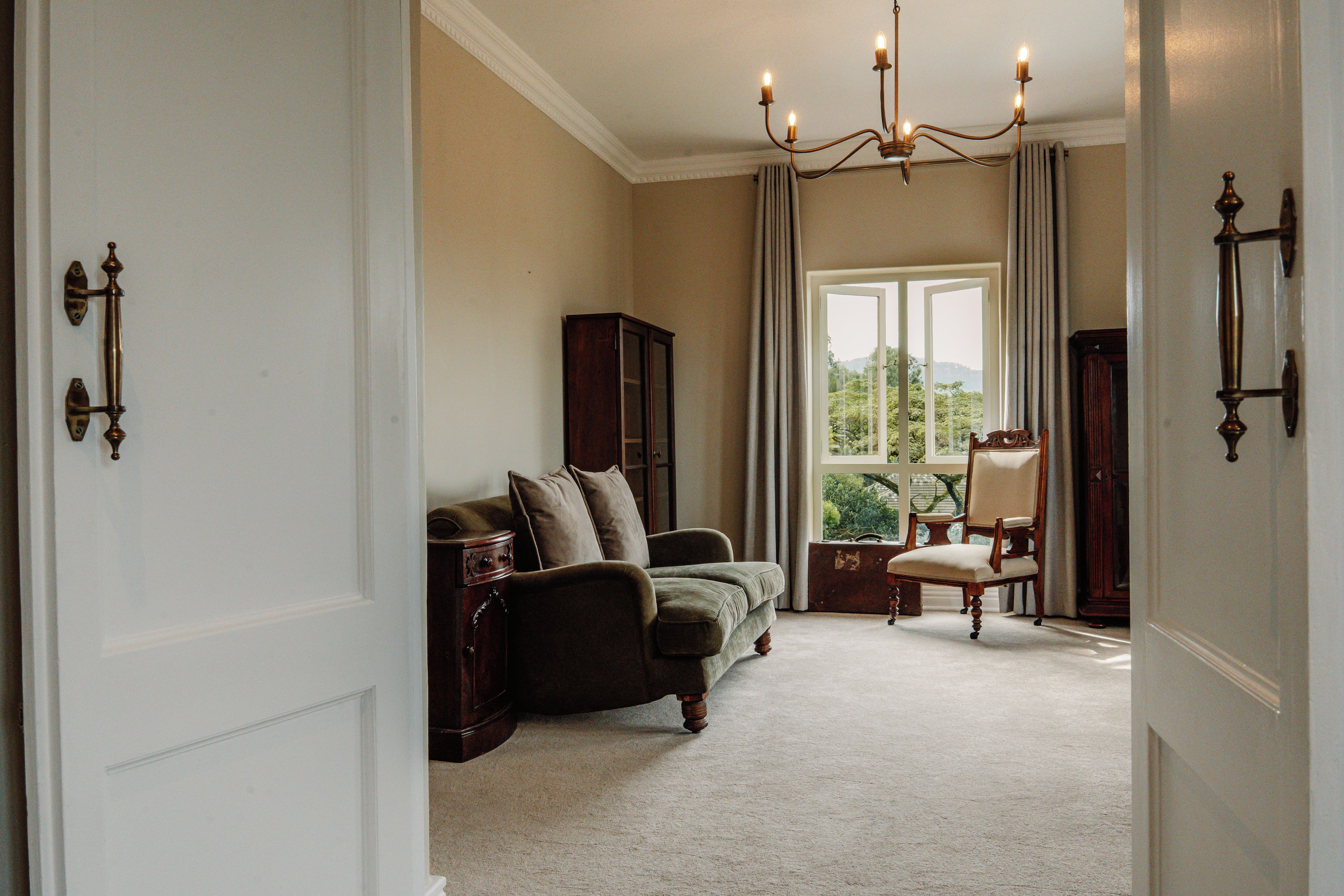 A room with a sofa, a chair, a cabinet, and a window with a view.