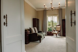 A room with a sofa, a chair, a cabinet, and a window with a view.