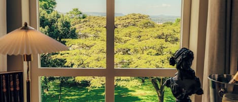 A dining table with various dishes, a view of a green landscape through a window, and a statue.