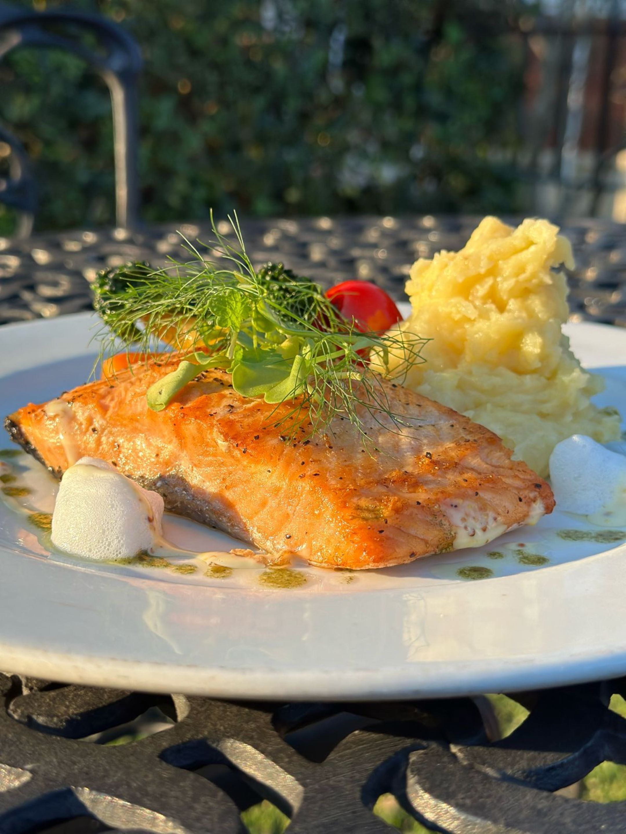 Une assiette de saumon, garnie d’aneth, accompagnée d’une portion de purée de pommes de terre.