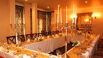 A long dining table set for a formal event with multiple candle holders, chairs, and a mirror on the wall.