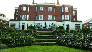 A large, multi-story brick building with a symmetrical facade, multiple windows, and a central entrance with steps leading up to it. - Redlands Hotel (Pietermaritzburg)