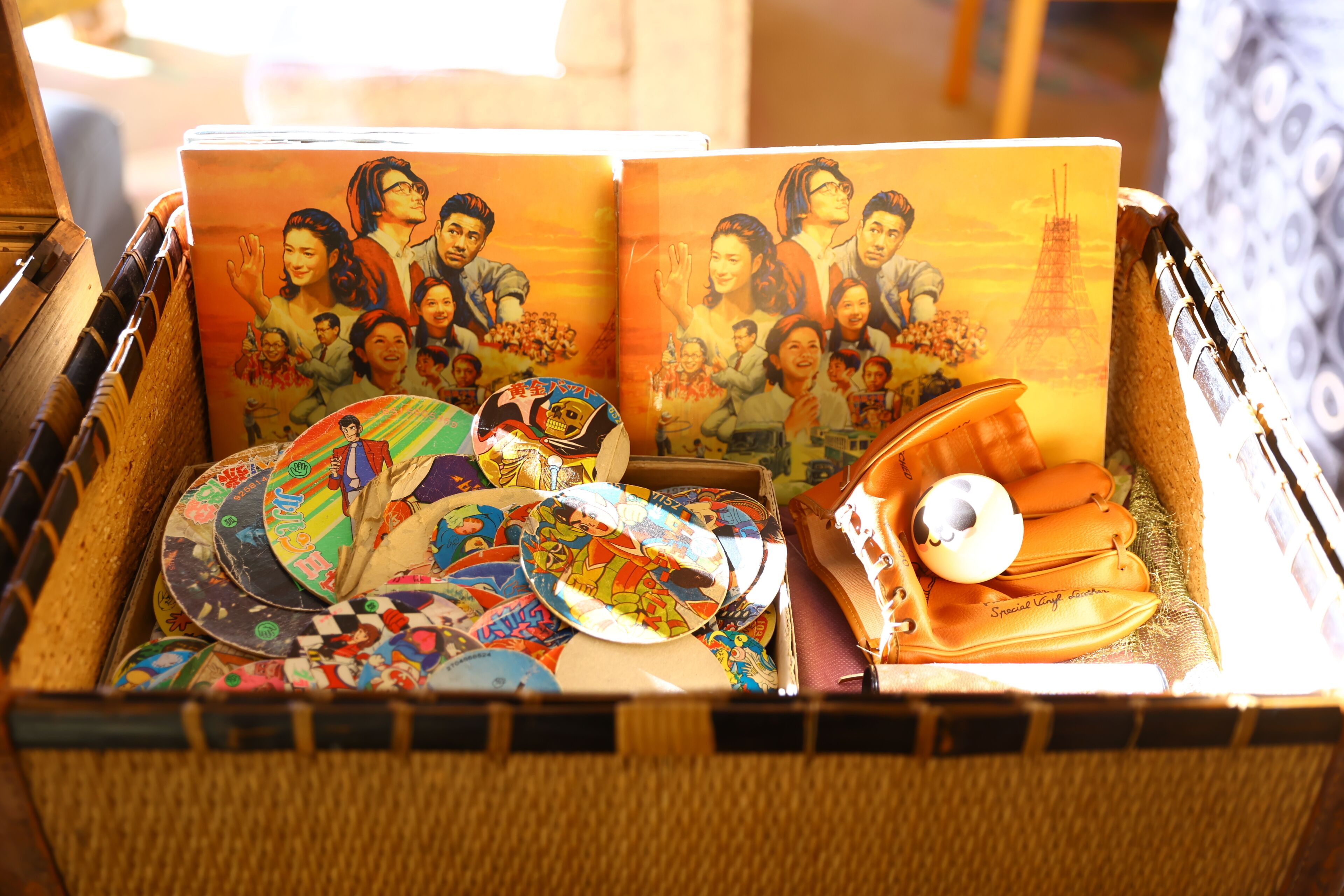 A wicker basket filled with various items including a book, colorful plates, and a pair of shoes.