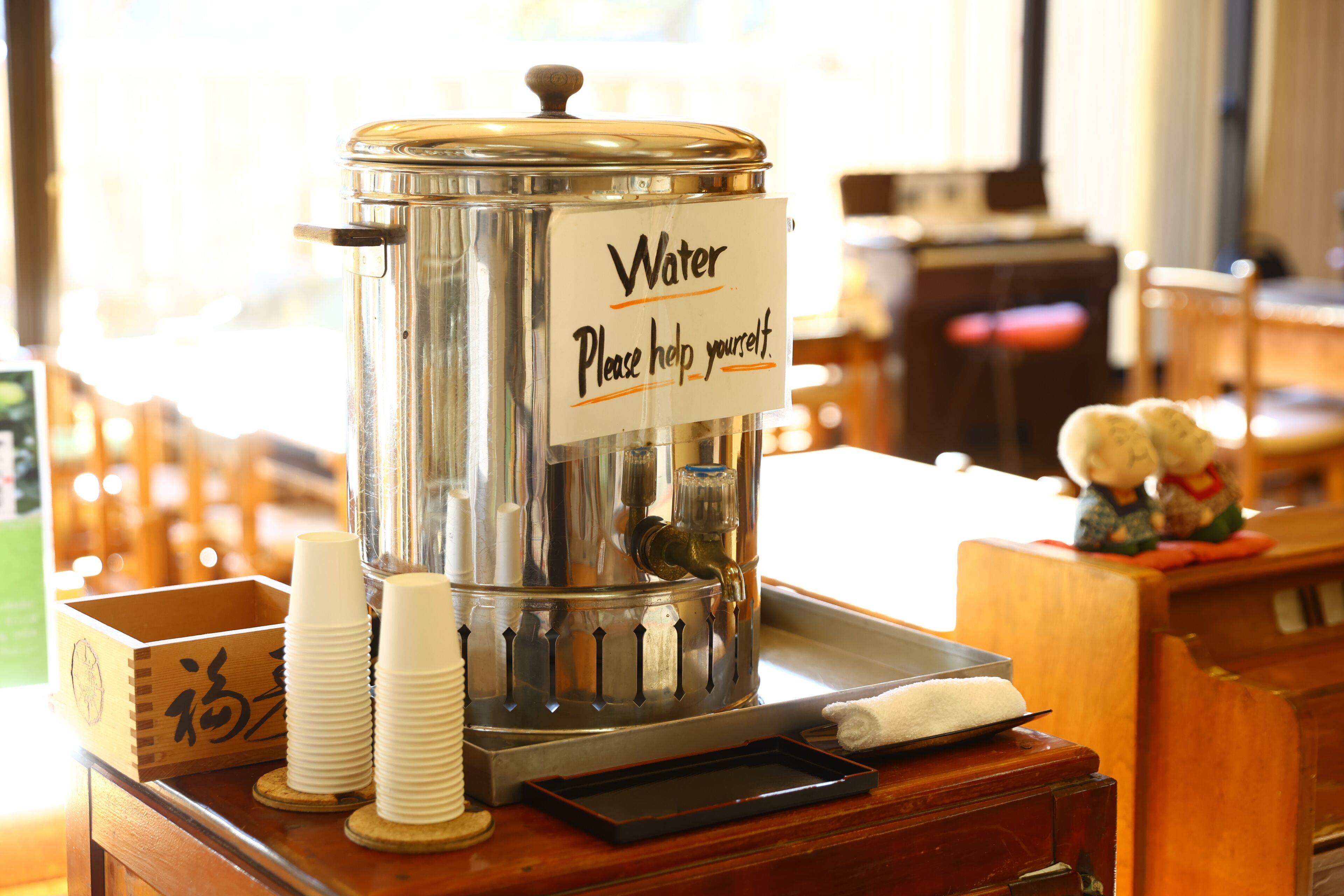 A water dispenser with a sign that reads "Water Please help yourself."
