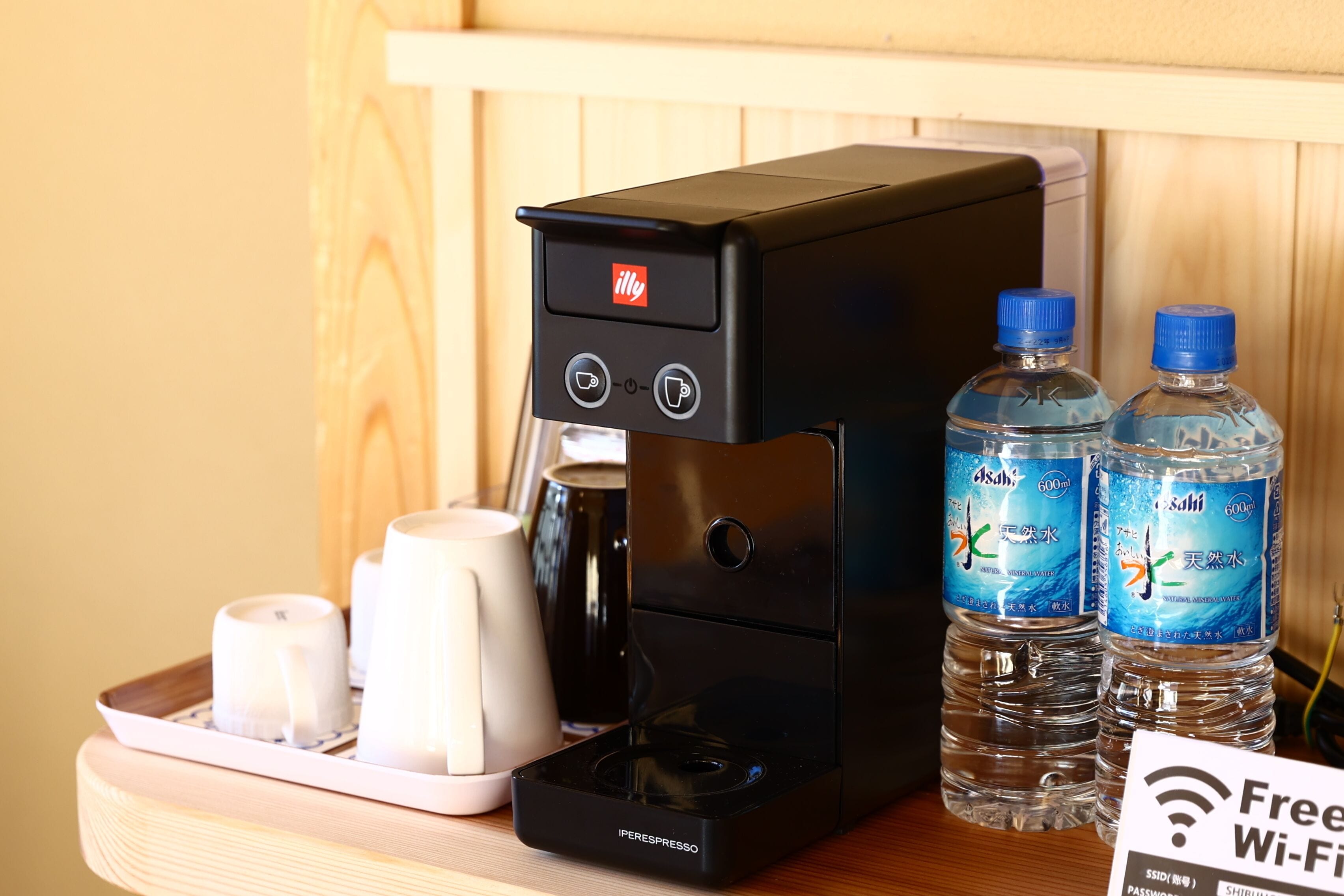 A coffee machine with a control panel, two water bottles, and a tray with cups and a teapot.
