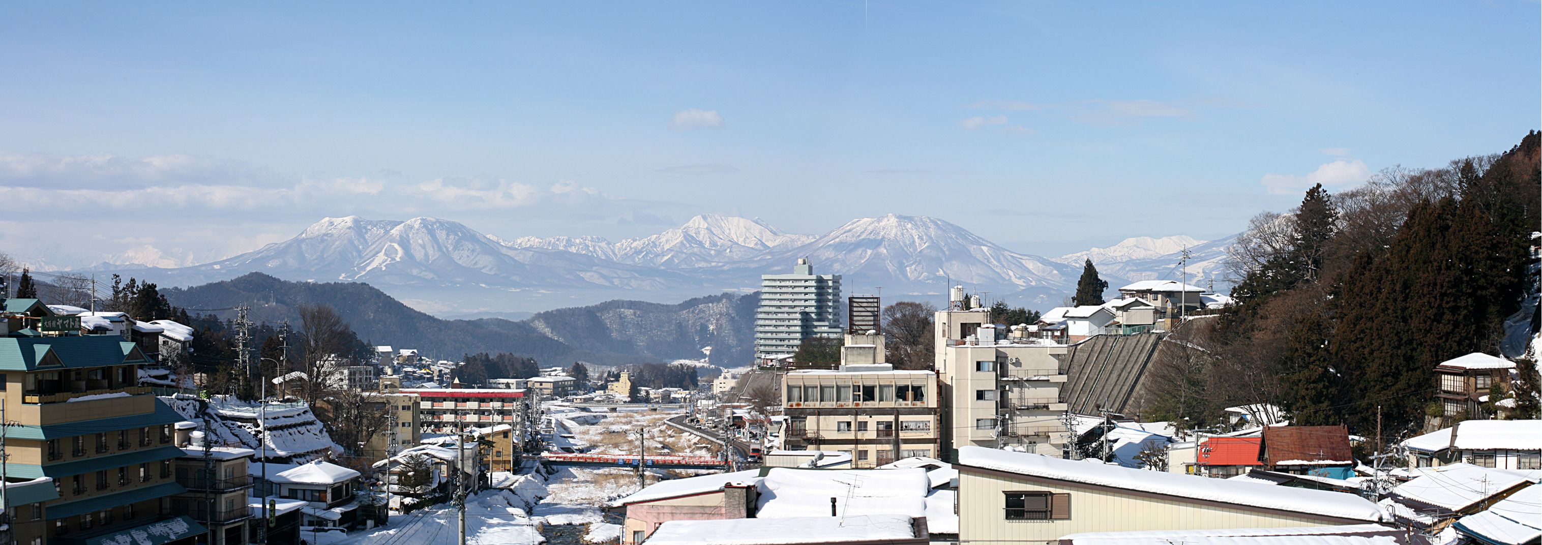 A town with buildings and snow-covered mountains in the background.