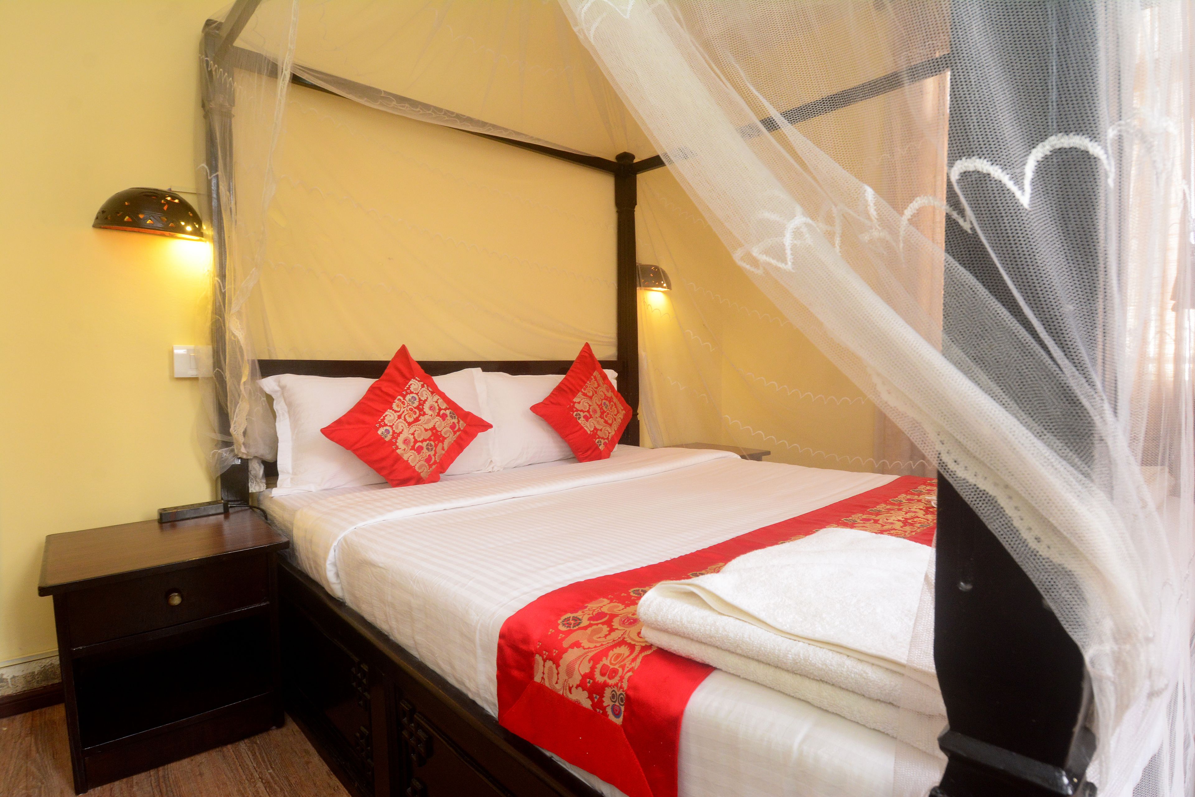 A neatly made bed with a canopy, two bedside lamps, and a nightstand.