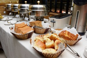 Una mesa de buffet con diversas opciones de panadería y comida caliente.