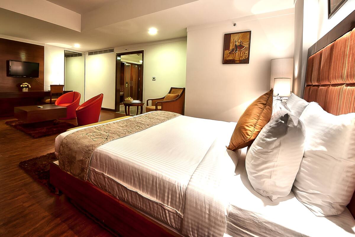 Une chambre d’hôtel avec un grand lit, une télévision, une chaise et un bureau.