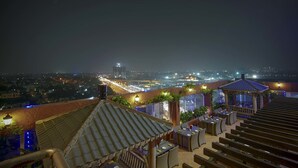 A rooftop terrace with outdoor seating and a view of a cityscape at night. - JP Hotel (Chennai)