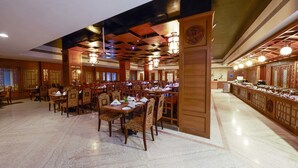 A spacious restaurant with wooden furniture and a marble floor. - JP Hotel (Chennai)