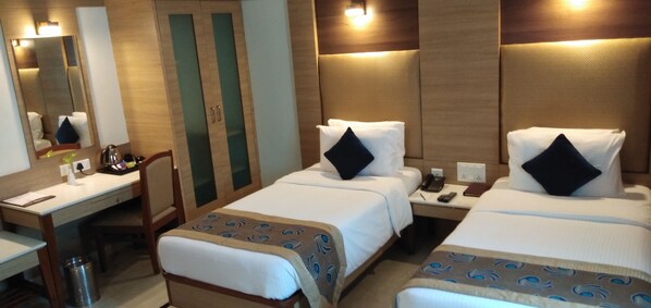 A hotel room with two beds, a desk, and a mirror. - JP Hotel (Chennai)