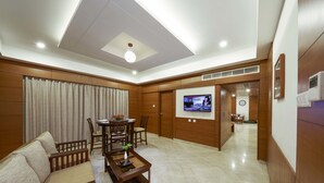 A modern living room with a sofa, coffee table, and TV. - JP Hotel (Chennai)