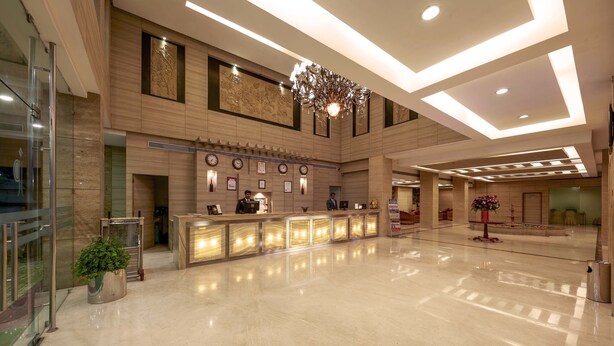 A spacious lobby with a reception desk, a large chandelier, and a polished marble floor. - JP Hotel (Chennai)