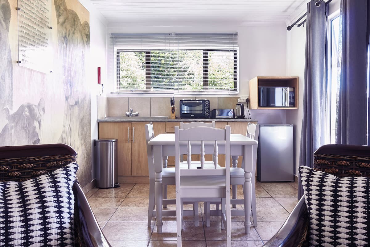 Une cuisine compacte comprenant une table à manger, des chaises, un four à micro-ondes et un réfrigérateur.