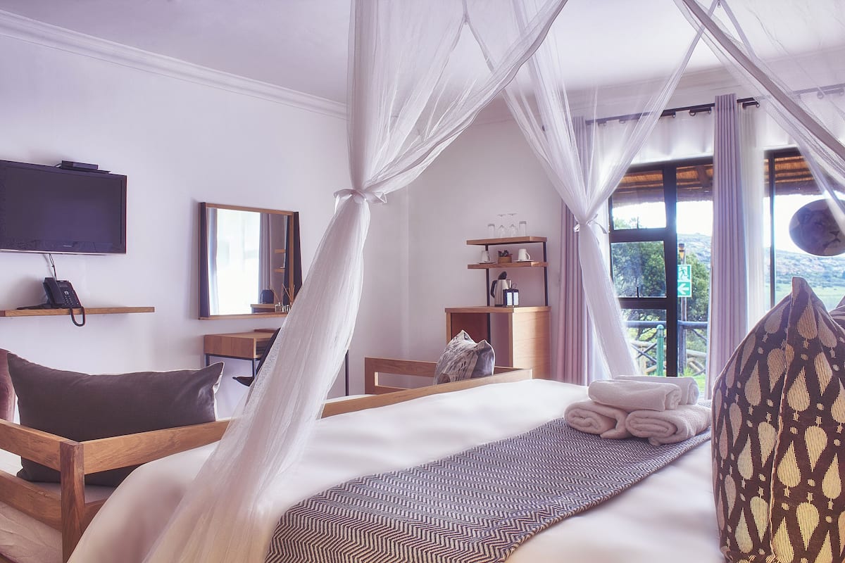 Une chambre à coucher comprenant un lit, une télévision, une table de chevet, une armoire et une fenêtre donnant sur un beau paysage.