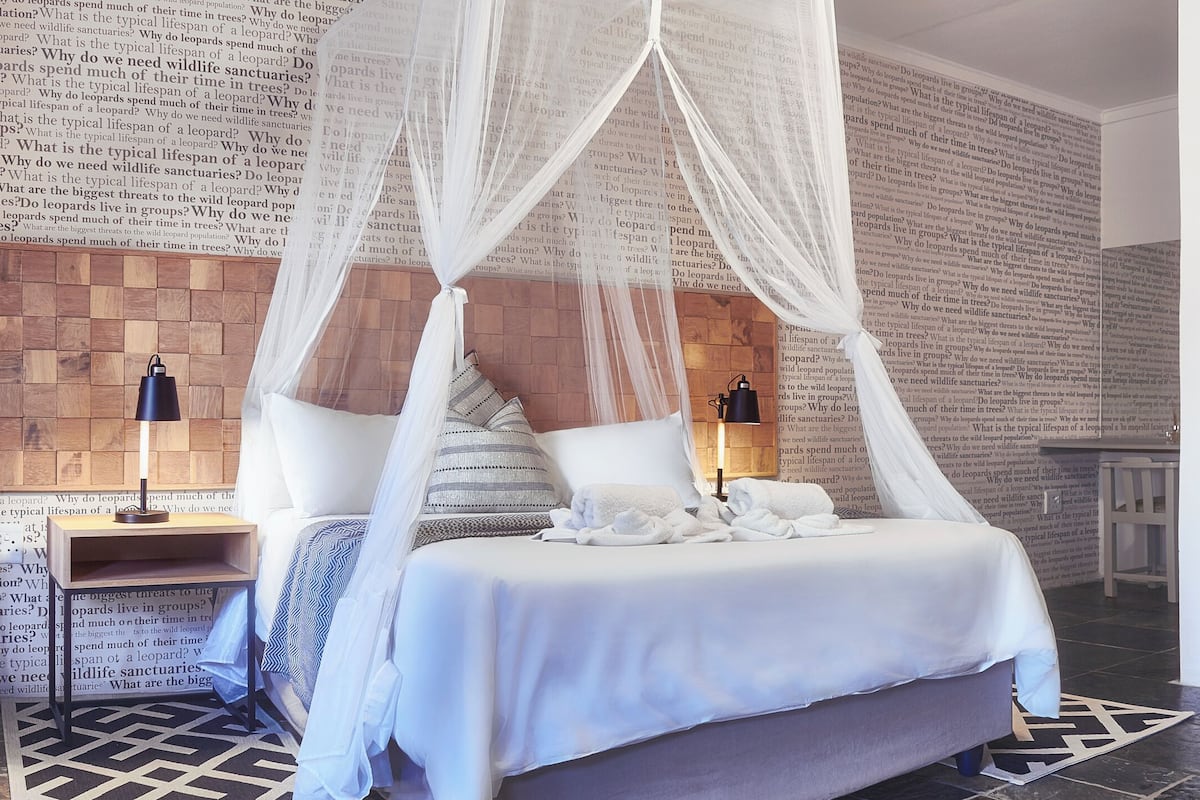 Une chambre à coucher avec un lit à baldaquin, une table de chevet et un grand mur décoré d’un motif léopard.