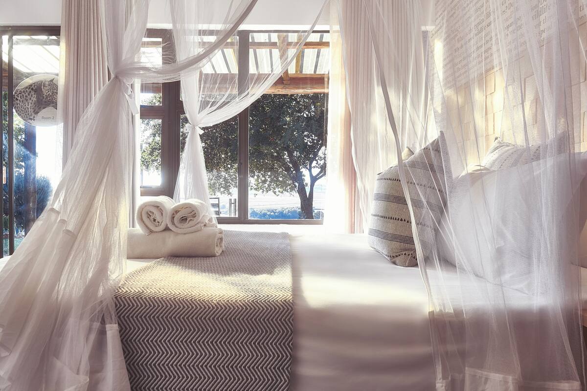 Une chambre à coucher avec un lit, une fenêtre et un arbre à l’extérieur.