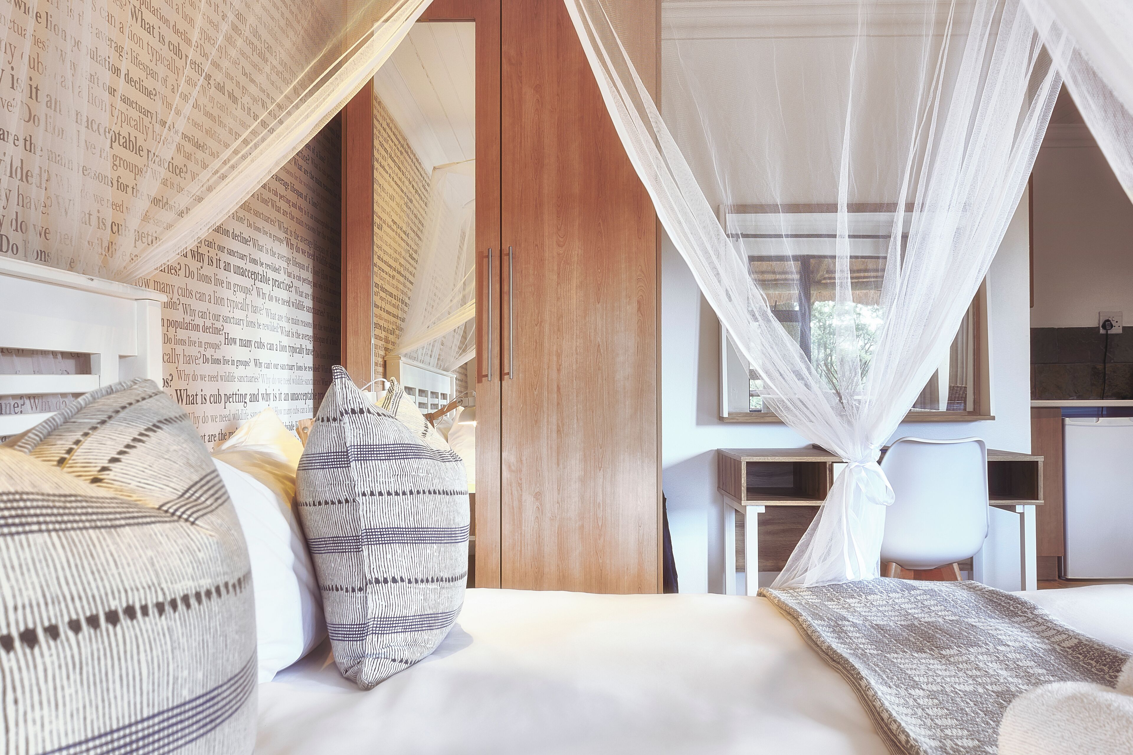 Ein Schlafzimmer mit einem Bett, Kissen, einem Holzschrank, einem Schreibtisch und einem Stuhl.