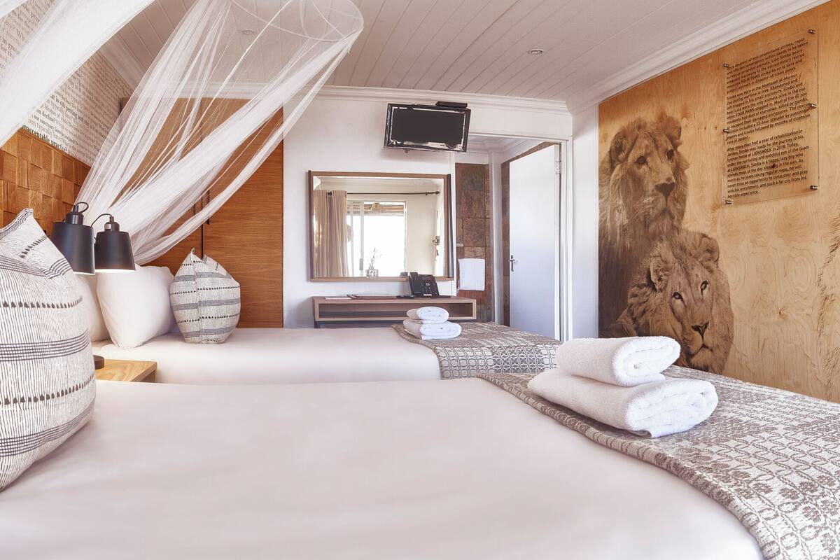 Une chambre avec une grande fresque représentant un lion, un lit à baldaquin et une vue sur la salle de bain.