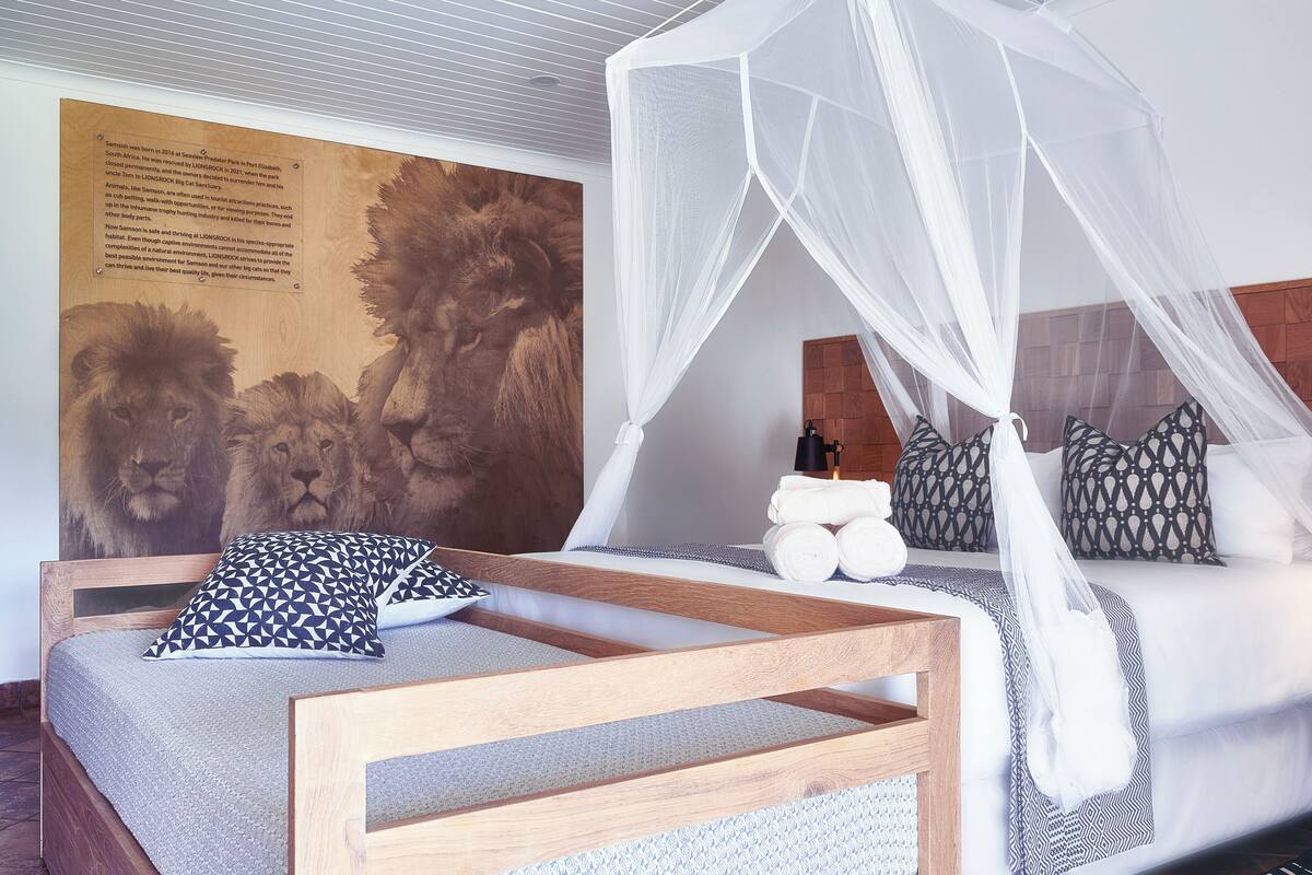 Une chambre avec un lit en bois, un lit à baldaquin, une fresque représentant un lion et un panneau d’information fixé au mur.