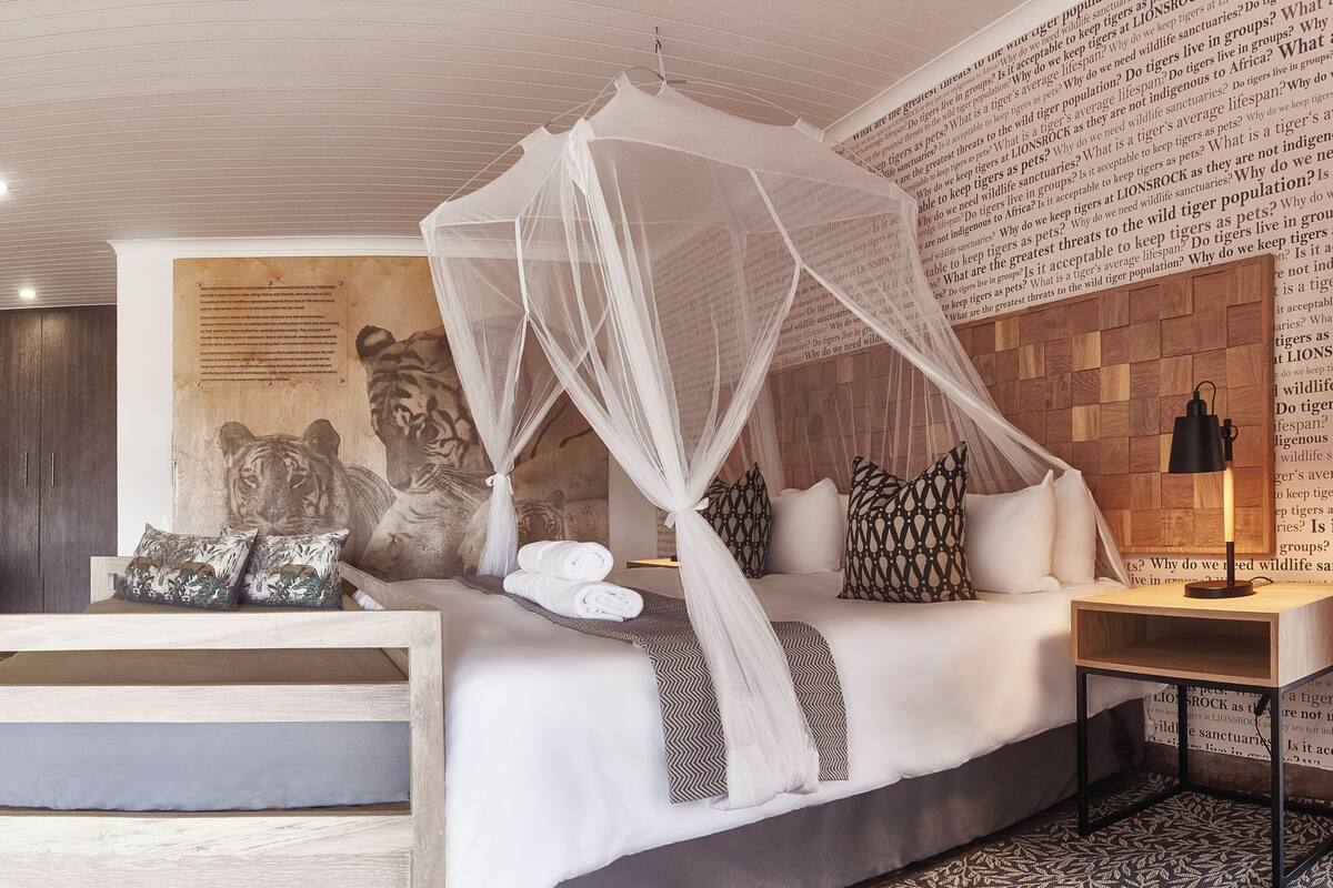 Une chambre à coucher avec un lit à baldaquin, une fresque représentant un tigre et un mur recouvert de motifs imprimés.