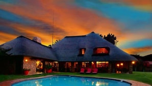 Una casa con techo de paja y una piscina delantera.