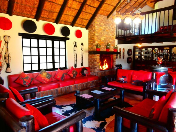 Una sala de estar acogedora con sofás rojos, una chimenea y una pared de ladrillo.
